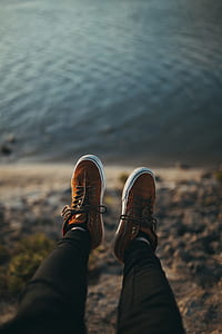 person wearing brown lace-up sneakers and black pants near body of water duing daytime thumbnail
