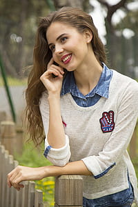 woman leaning on brown wooden fence thumbnail