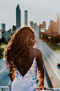 woman in sequinned silver spaghetti strap dress holding on bridge rails thumbnail