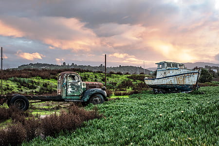 brown and green single can pickup truck near white and black boat at daytime thumbnail