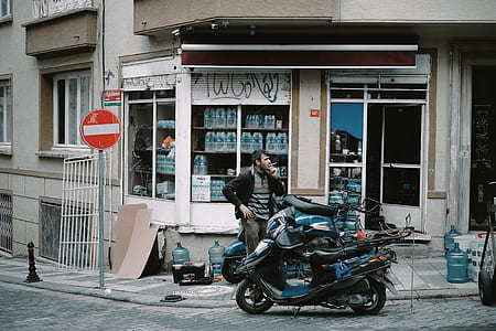 person smoking beside black motor scooter during daytime thumbnail