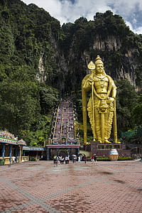 group of people walking beside gold Hindu god statue thumbnail