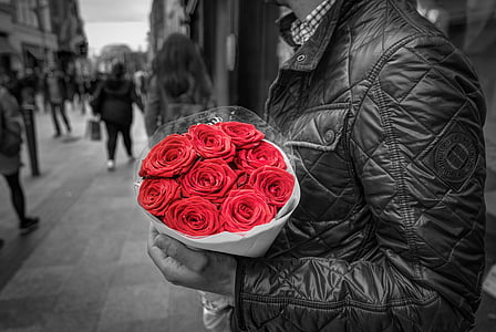 selective color photography of man holding bouquet of red roses thumbnail