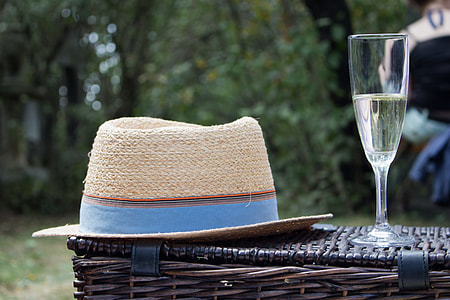 selective focus photography of fedora hat beside champagne flute on wicker basket thumbnail