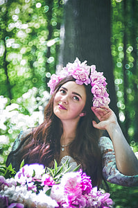 woman in white floral shirt holding pink and white flower bouquet with pink flowers headdress thumbnail