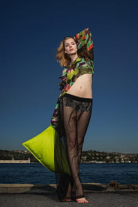 woman holding pillow near body of water thumbnail