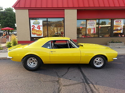 yellow muscle car parked near red building thumbnail