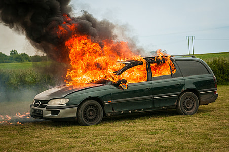 green station wagon burning on green grass field during daytime thumbnail