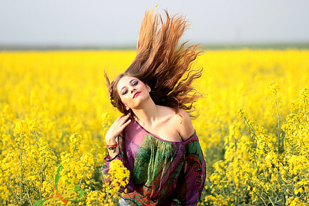woman wearing purple and green off-shoulder top in yellow rapeseed flower field thumbnail