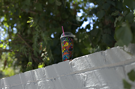 black disposable cup on top of gray brick wall thumbnail