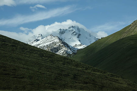snowy mountain in between green mountains thumbnail