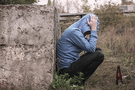 person in blue hoodie leaning on concrete brick thumbnail