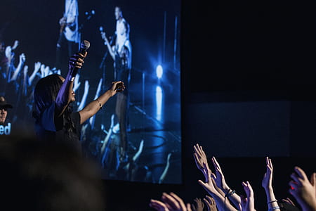 woman on stage raising her hands in front of people thumbnail