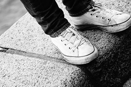 grayscale photography of standing person wearing jeans and lace-up shoes thumbnail