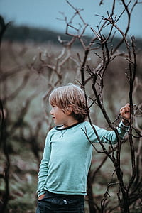 boy standing beside bare tree thumbnail