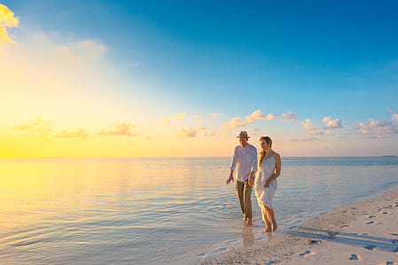 Couple Walking on Seashore Wearing White Tops during Sunset thumbnail