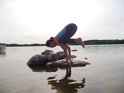 woman doing yoga on top of stone in body of water during daytime thumbnail