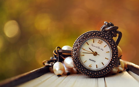 selective focus photo of round gold-colored Quartz analog watch on brown surface thumbnail