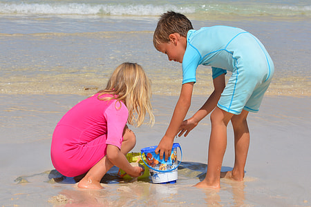 girl and boy gathering brown wet sand near beach thumbnail