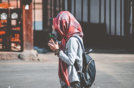 woman standing on sidewalk near brown building during daytime thumbnail