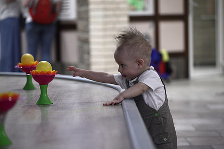 kid reaching plastic toys on brown table selective focus photo thumbnail