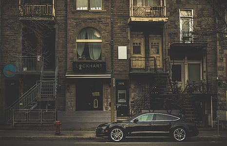 black sedan parked near building at daytime thumbnail