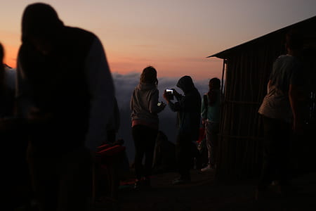 two people holding camera beside brown hut during daytime thumbnail