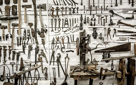 assorted tools hanging on white wooden wall thumbnail