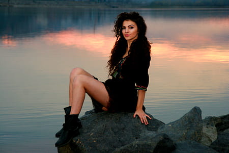 woman wearing black rompers on rock near body of water thumbnail