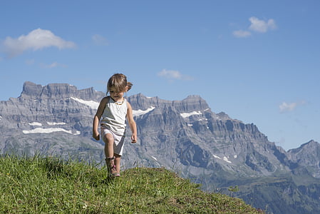 girl standing on grasses within mountain range thumbnail