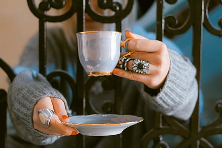 woman holding blue ceramic cup and saucer thumbnail