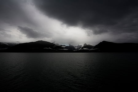 grayscale photography of ocean and mountain thumbnail