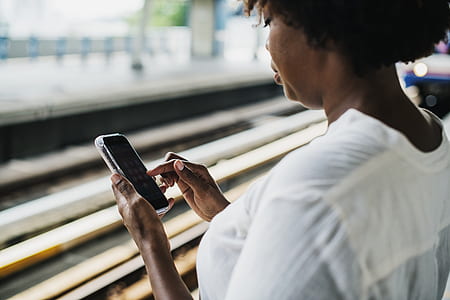 woman in white shirt holding black smartphone thumbnail
