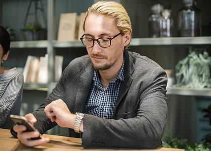man looking at watch while sitting near table thumbnail