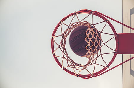 brown Spalding basketball on red basketbal ring thumbnail