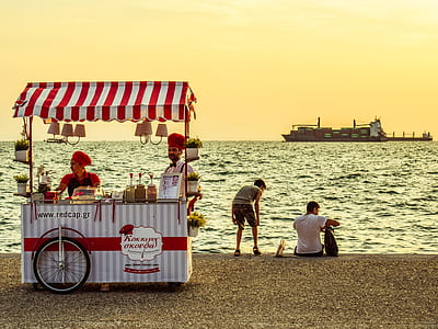 two person standing beside food cart near beach thumbnail