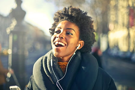 A young african woman with culy hair listening to music with earphones on a winter day thumbnail