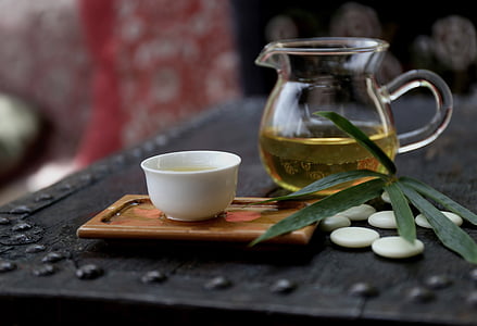 clear glass teapot and white ceramic teacup on black table thumbnail