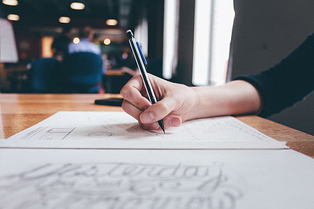 person holding pen in front of table selected photography thumbnail