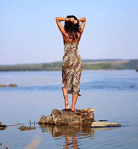 woman standing on brown rock near water during daytime thumbnail