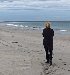 woman walking at seashore under white clouds thumbnail