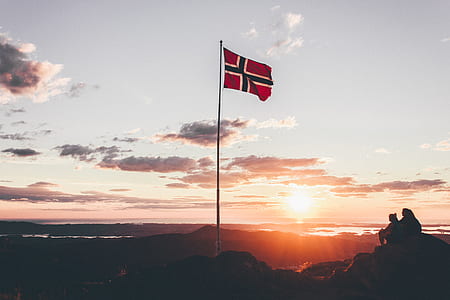 silhouette of people on peak of mountain with flag during golden hour thumbnail