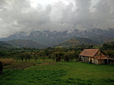 barn in middle of field with mountain in background thumbnail