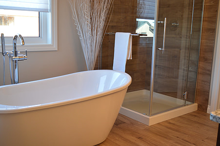 white ceramic bathtub beside a clear glass shower enclosure and an open window thumbnail