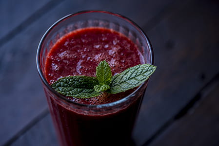 clear drinking glass with red liquid on top of brown surface thumbnail