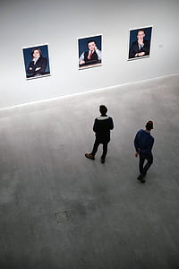 men in blue and black jackets while looking at three posters thumbnail