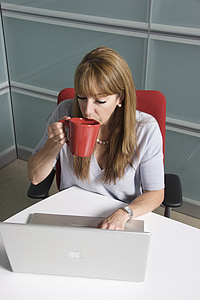 woman holding mug while looking at MacBook thumbnail