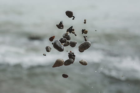 Close up of pebble stones floating in the air after being thrown with blurred background thumbnail
