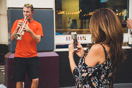 Woman Taking Photo of Man Playing Trumpet thumbnail
