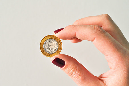 person holding round silver-and-gold-colored coin thumbnail